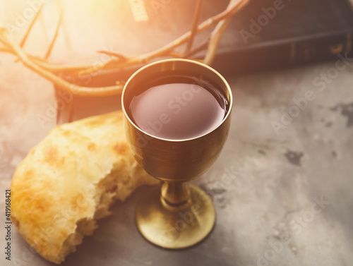 Chalice of wine and bread on grunge background photo