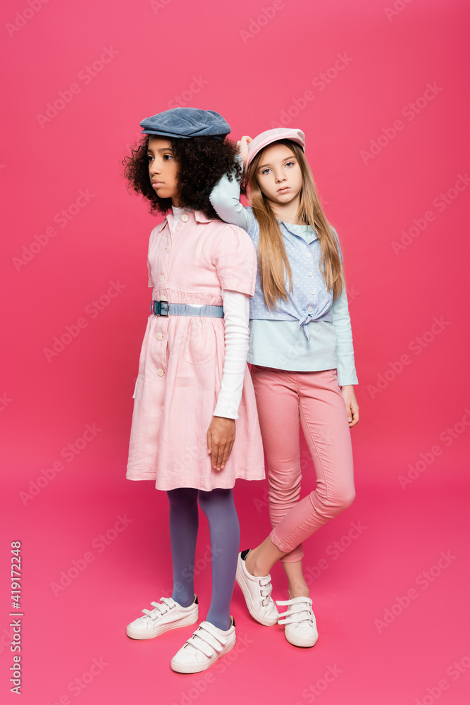 stylish girl leaning on shoulder of african american friend while posing on pink stylish girl leaning on shoulder of african american friend while posing on pink