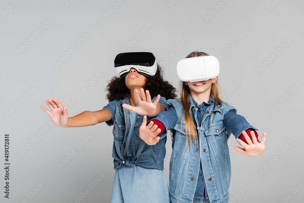 excited multicultural kids in stylish denim clothes gesturing in vr headsets on grey excited multicultural kids in stylish denim clothes gesturing in vr headsets on grey