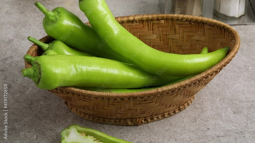 Basket with fresh green turkish carliston peppers an a halved one in front Basket with fresh green turkish carliston peppers an a halved one in front