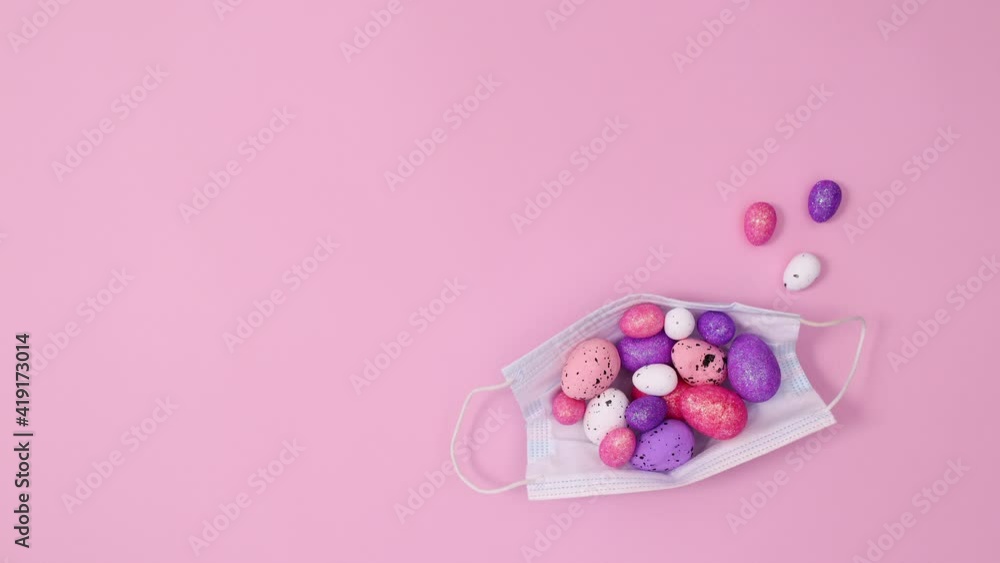 Easter eggs appear on face mask on pastel pink background. Minimal flat lay Stop motion Easter eggs appear on face mask on pastel pink background. Minimal flat lay Stop motion