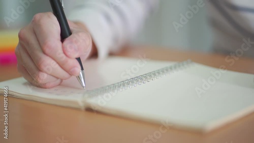 Indoor shot of Men hand with casual dress using pen to writing down and take note on the plain white paper while work or learn from home. Business and education concept new normal. 