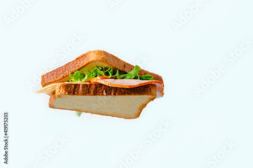 A sandwich with cheese and meat hangs in the air on a white background