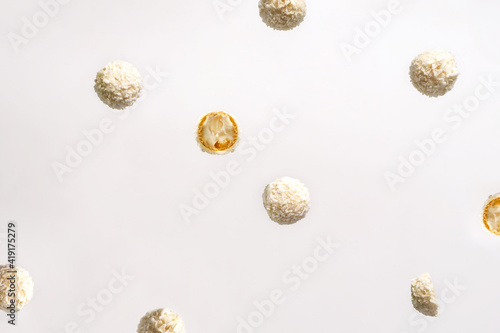 Candies in coconut chips are tossed in the air on a white background. Beautiful background