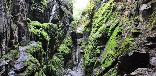 A rocky crevice covered with moss and an iron staircase
