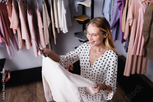 High angle view of pleased showroom proprietor holding hanger with jacket photo