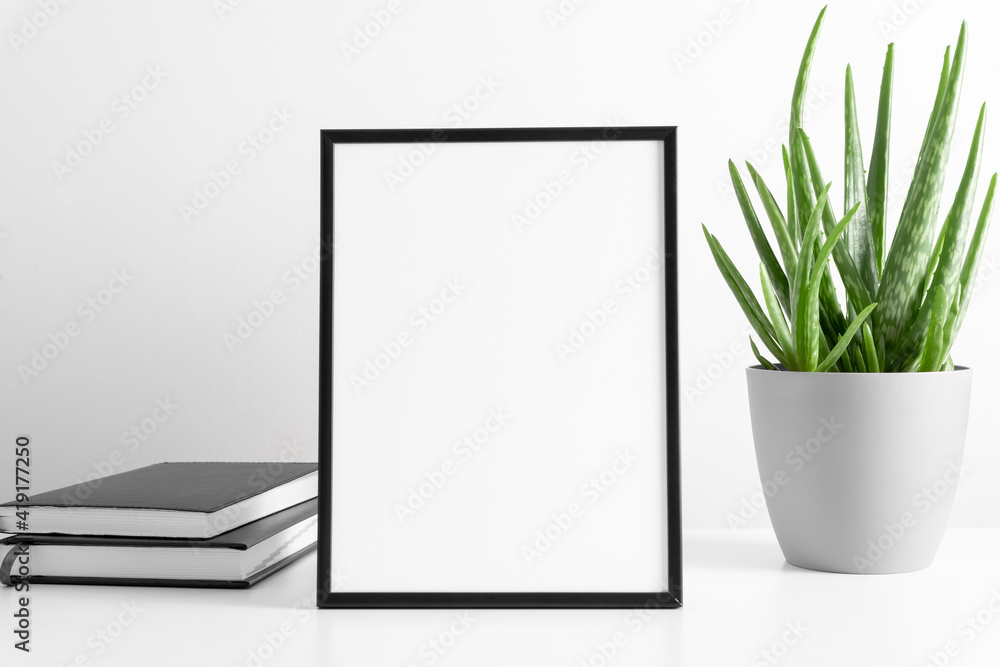 Black frame mockup with workspace accessories and aloe vera on white table. Front view. Place for text, copy space, mockup - obrazy, fototapety, plakaty 