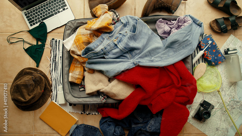 Fotografia Top view on suitcase lay on floor with mess inside and around it