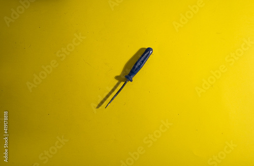 The old screwdriver on the yellow background with traces of dirt photo