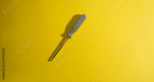 The old screwdriver on the yellow background with traces of dirt photo