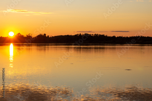 A colorful sunny sunset is reflected on the surface of the calm lake. © Анатолий Савицкий