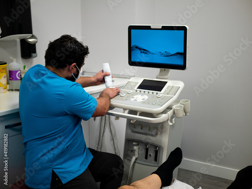 PHYSIOTHERAPIST IN HIS CLINIC PERFORMING AN ULTRASOUND SCAN