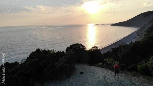 Aerial cinematic: a drone flying along the seashore at sunset. The drone is flying over the sea. Beautiful summer seascape of the sea. Top view of the rocks