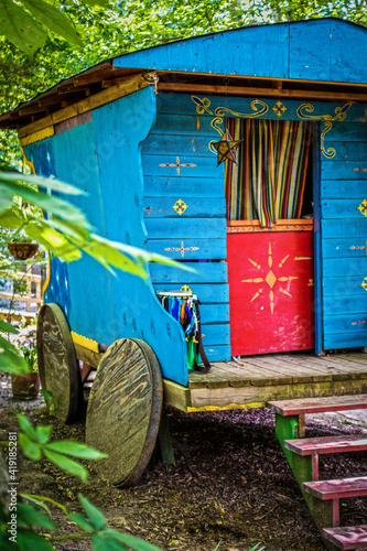 Canvas Print Blue and brightly painted wooden gypsy caravan parked in woods