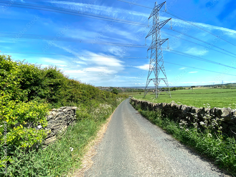 Looking along, Deep Lane, with dry stone walls, fields and pylons, on a sunny day near, Bradford, Yorkshire, UK Looking along, Deep Lane, with dry stone walls, fields and pylons, on a sunny day near, Bradford, Yorkshire, UK
