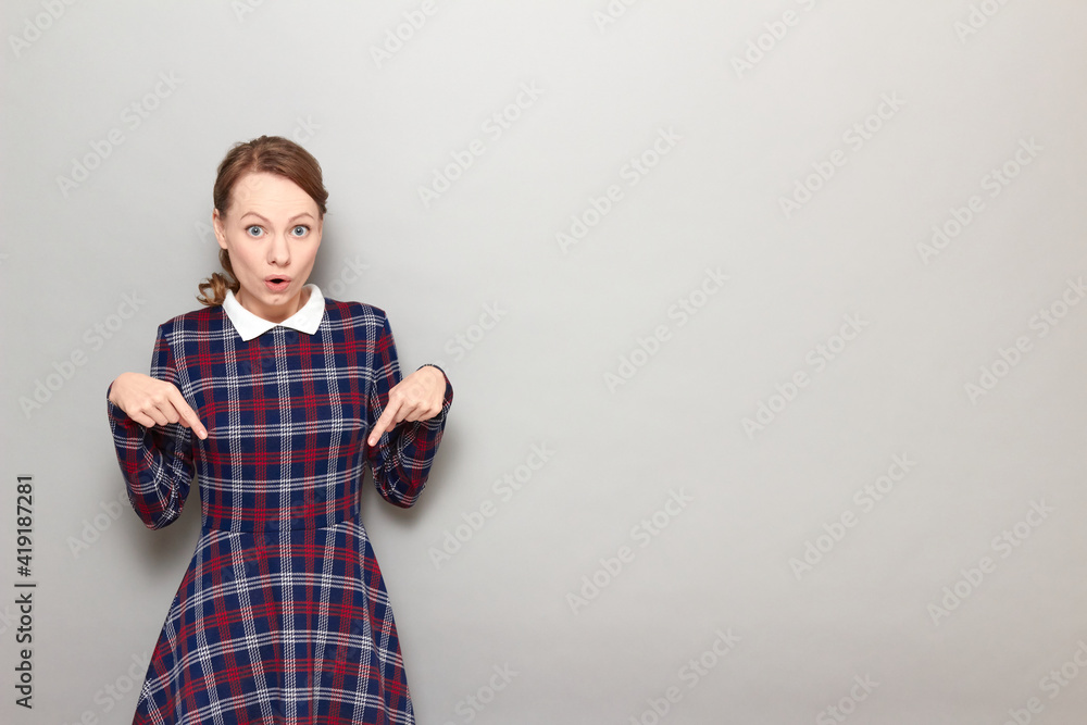 Portrait of amazed girl pointing with fingers downwards at copy space Portrait of amazed girl pointing with fingers downwards at copy space