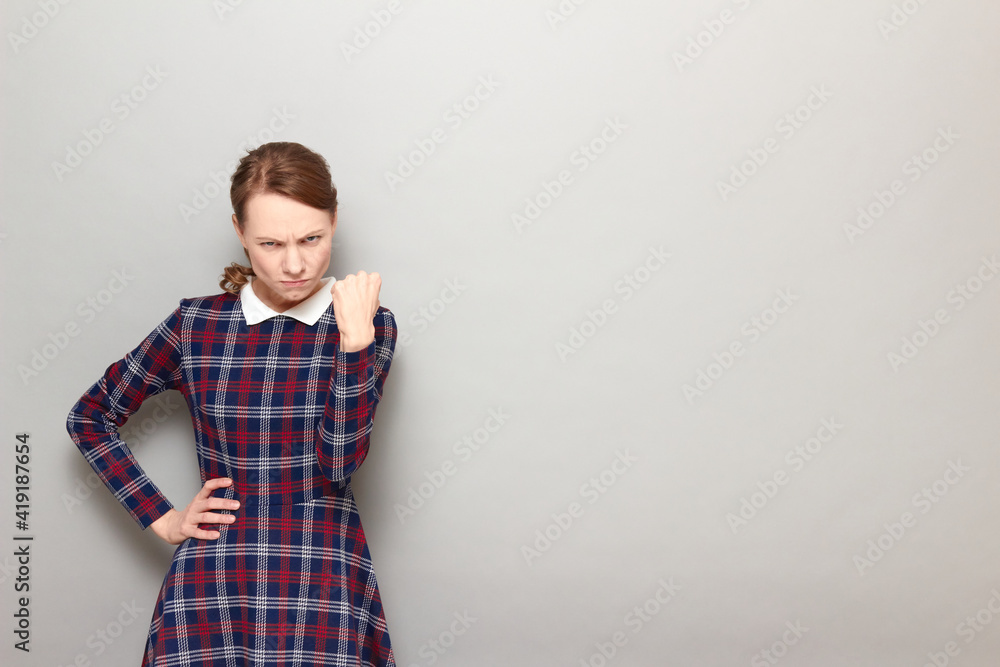 Portrait of funny angry girl shaking fist in threatening gesture Portrait of funny angry girl shaking fist in threatening gesture