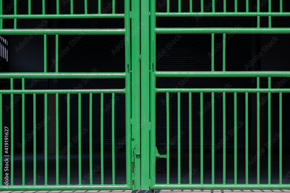 Front view of green metal gate of parking garage on dark background Front view of green metal gate of parking garage on dark background