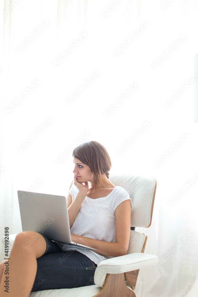 Fototapeta premium Young woman with laptop in her comfortable apartment