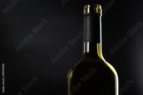 one open bottle of wine without a label on a dark glossy background.