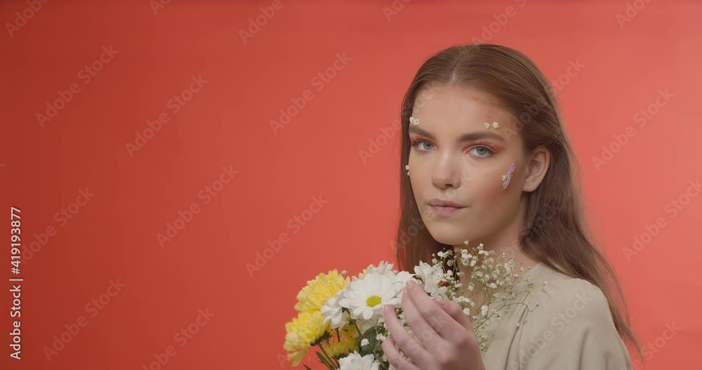 Beautiful young woman with creative spring makeup and bouquet of flowers on color background Beautiful young woman with creative spring makeup and bouquet of flowers on color background