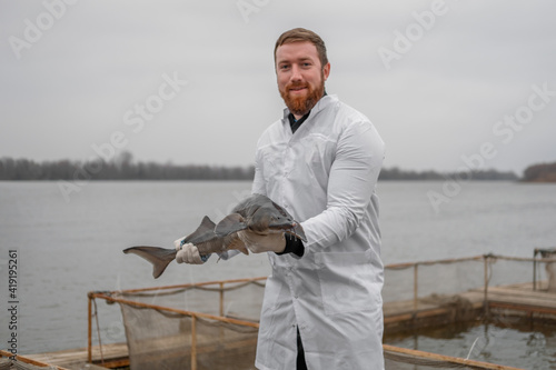 Foto sturgeon on a sturgeon farm( aquafarm), a blurry man holding a sturgeon in the b