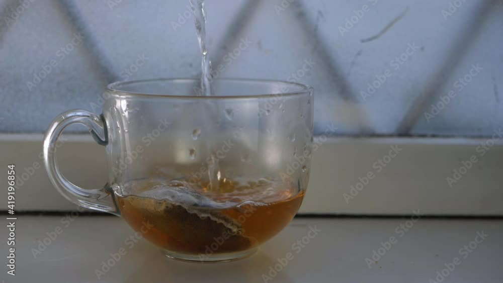 Pouring hot water into mug with tea bag Pouring hot water into mug with tea bag