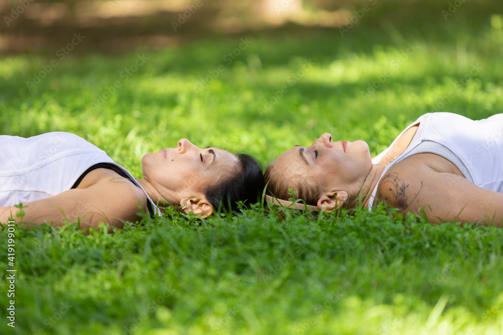 Women practicing yoga in the savasana pose outdoors on sunny day, Barueri, São Paulo, Brazil Women practicing yoga in the savasana pose outdoors on sunny day, Barueri, São Paulo, Brazil