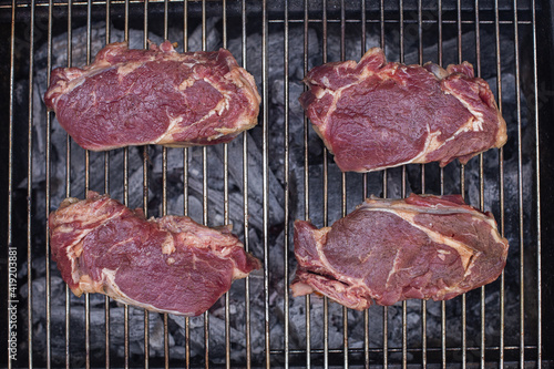 Beef steaks on a barbecue grill, top view