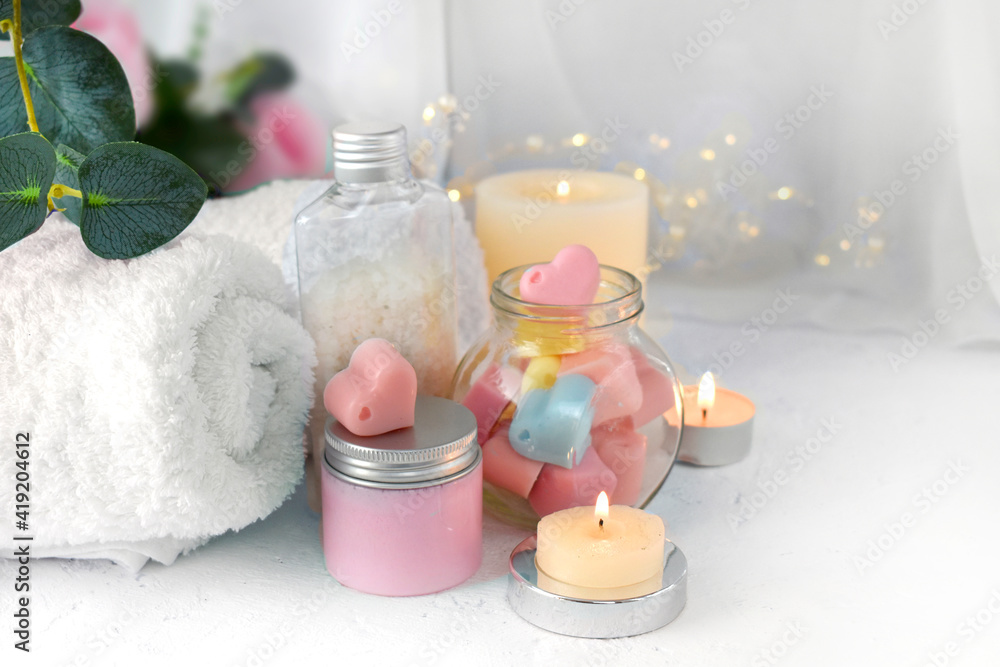 Spa aromatherapy composition with bath cosmetics on light background. Body care cream, heart shape soap and burning candles. Romantic concept for Mothers day, Valentines day or wedding. Spa aromatherapy composition with bath cosmetics on light background. Body care cream, heart shape soap and burning candles. Romantic concept for Mothers day, Valentines day or wedding.