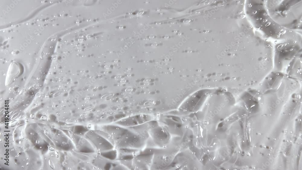 Transparent liquid gel background, clear serum texture. Motion, rotation of the beauty skincare product sample with bubbles. Top view. Macro Shot. High quality 4k footage Transparent liquid gel background, clear serum texture. Motion, rotation of the beauty skincare product sample with bubbles. Top view. Macro Shot. High quality 4k footage