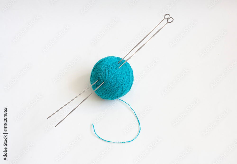 A skein of blue knitting thread and knitting needles on a white background A skein of blue knitting thread and knitting needles on a white background