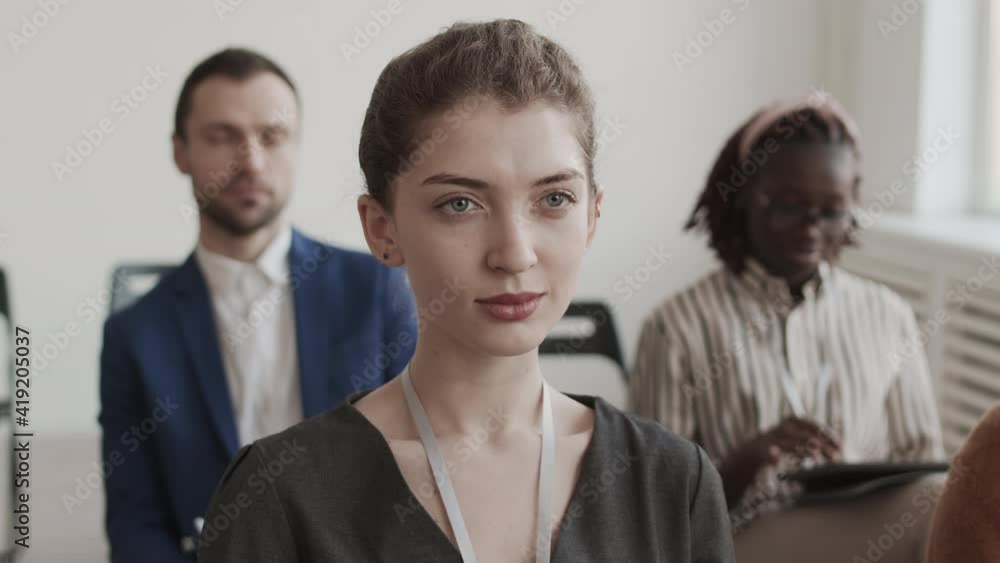 Medium close-up of young Caucasian businesswoman sitting in conference room, smiling, looking into distance Medium close-up of young Caucasian businesswoman sitting in conference room, smiling, looking into distance