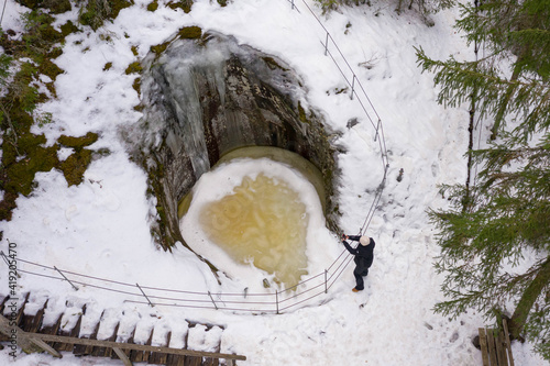 A woman admires the winter landscape in the forest. Photo from the drone. Glacial potholes in Askol, Finland. photo