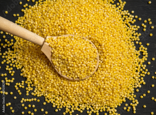 Millet. Millet in a wooden spoon and bowl on a wooden kitchen table photo