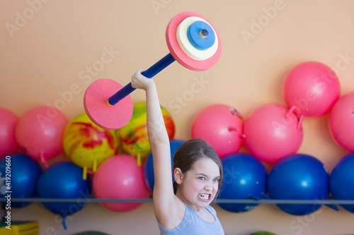 Little girl holding a barbell in the gym