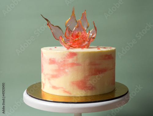 An edible red isomalt flower on top of a cake on a pale green background photo