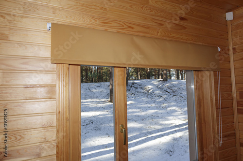 Interior with wooden walls and fabric roller blinds by the window