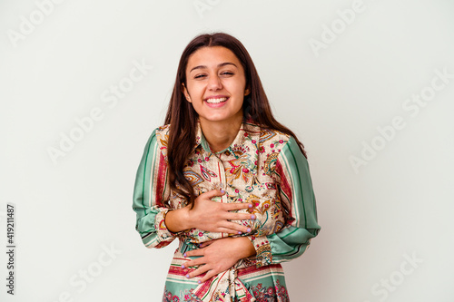 Young Indian woman isolated on white background laughs happily and has fun keeping hands on stomach.