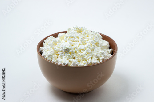 Cottage cheese on a white background. Homemade cottage cheese in a deep plate. Milk product