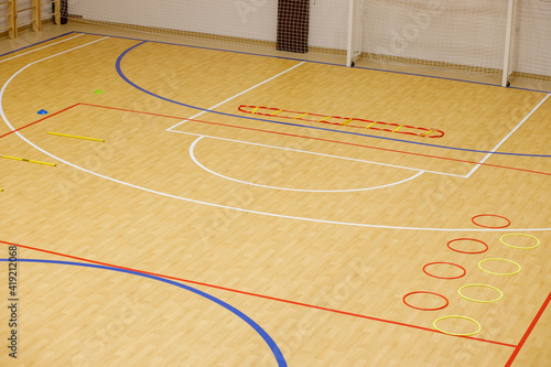 Gym for playing futsal, mini-football. Folded wooden parquet on the field of hall for mini-football. Futsal ball and bright line markings on the floor. Floor sports hall with bright lines of marking