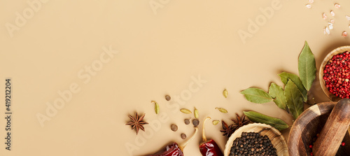 Fototapeta Naklejka Na Ścianę i Meble -  Creative food mockup with various types of spices Bay leaf, red chili pepper, anise in wooden bowls on a mocca beige color background with copy space. Long food banner with copy space.