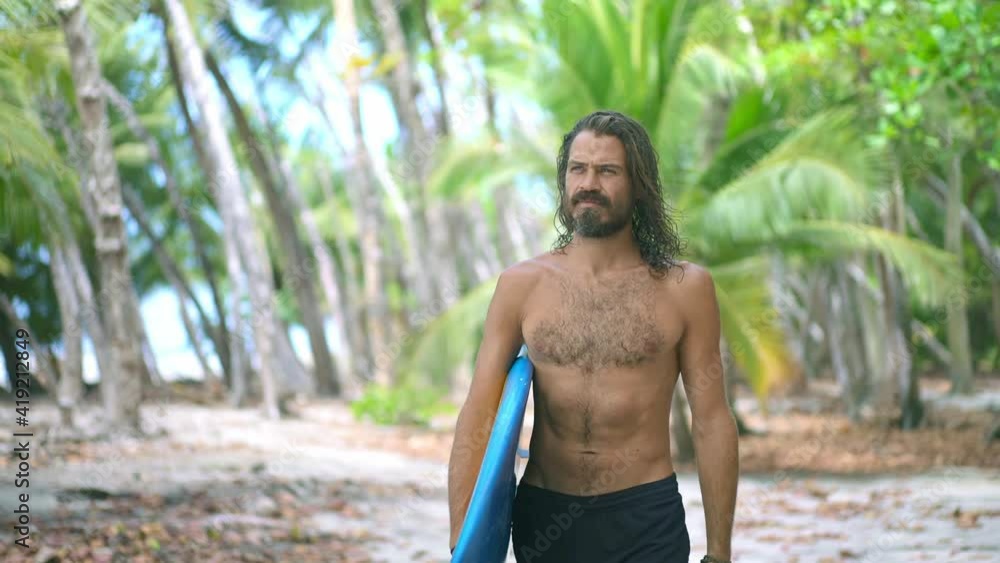 Beautiful young surfer man walk in jungle on the exotic tropical island. Concept of Fitness Healthy Active Living, Surfing. Summer Vacation. Slow motion. Beautiful young surfer man walk in jungle on the exotic tropical island. Concept of Fitness Healthy Active Living, Surfing. Summer Vacation. Slow motion.