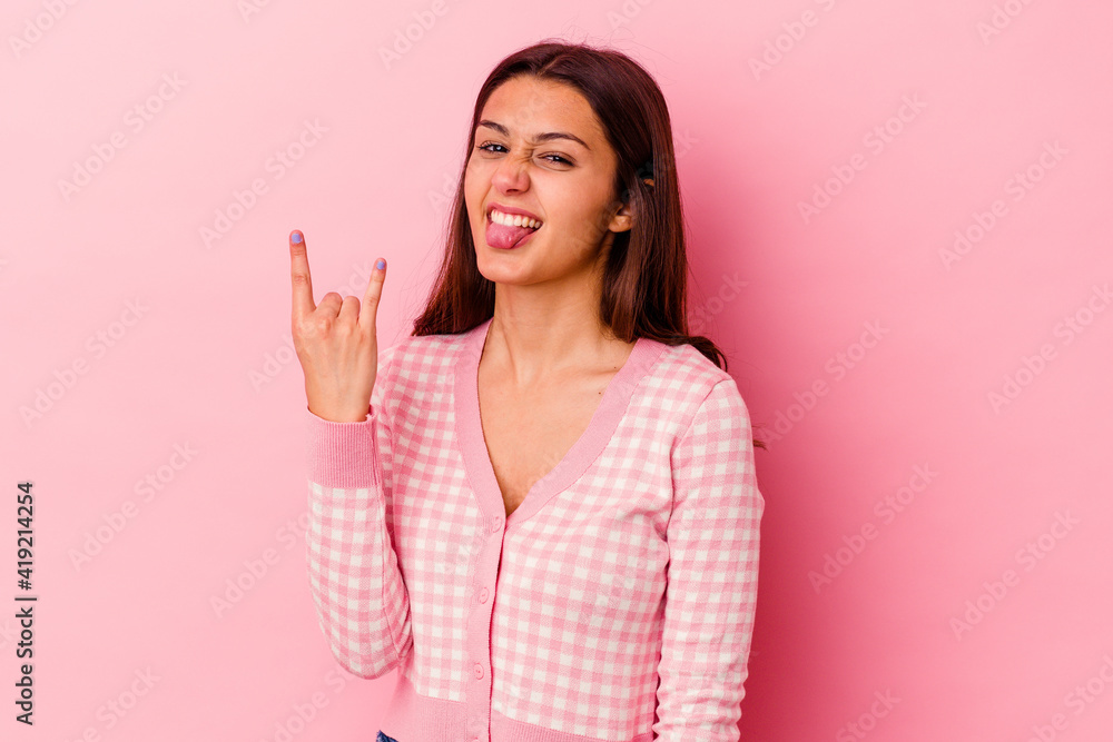 Young Indian woman isolated on pink background showing rock gesture with fingers Young Indian woman isolated on pink background showing rock gesture with fingers