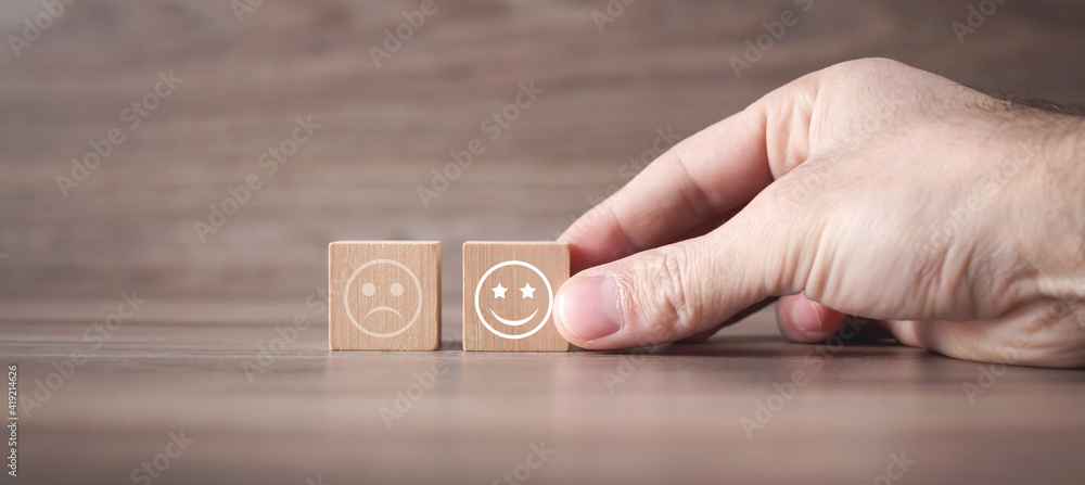Man showing sad and happy smileys on wooden cube. Customer satisfaction - obrazy, fototapety, plakaty 