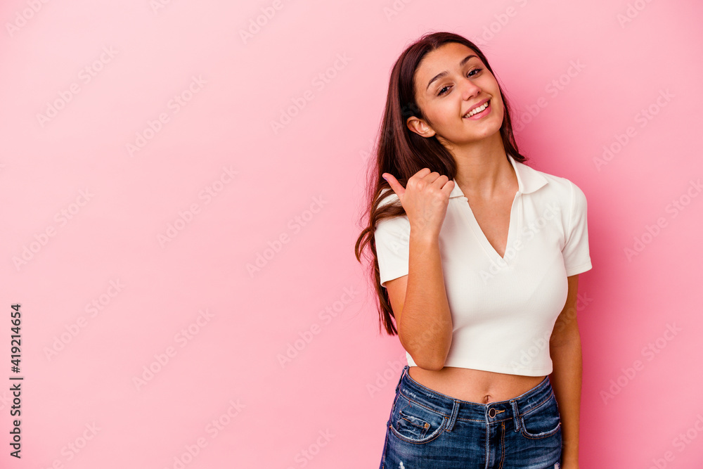 Young Indian woman isolated on pink background points with thumb finger away, laughing and carefree. Young Indian woman isolated on pink background points with thumb finger away, laughing and carefree.