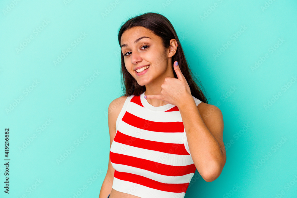 Young Indian woman isolated on blue background showing a mobile phone call gesture with fingers. Young Indian woman isolated on blue background showing a mobile phone call gesture with fingers.