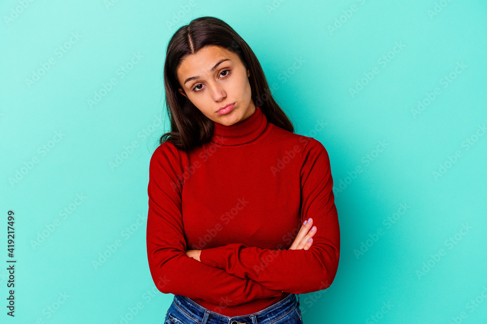 Young Indian woman isolated on blue background who is bored, fatigued and need a relax day. Young Indian woman isolated on blue background who is bored, fatigued and need a relax day.
