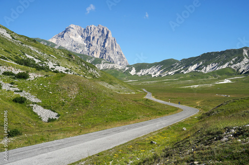 Road to Corno Grande Mountain, highest mountain of Apennine Mountains with grassy landscape, Gran Sasso National Park, Abruzzo, Italy, travel and climbing concept