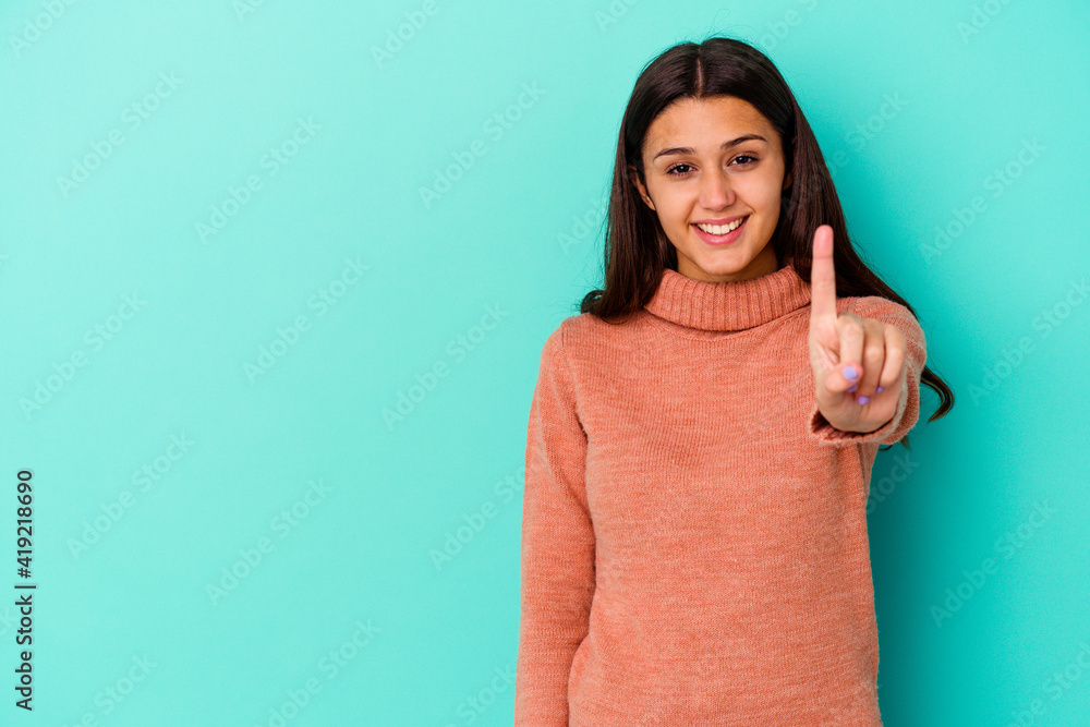 Young Indian woman isolated on blue background showing number one with finger.